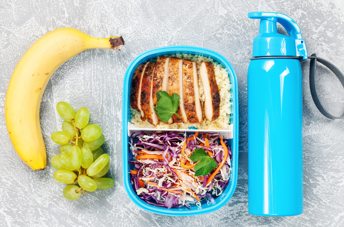 banana, grapes and container with chicken and vegetables divided and thermos beside it