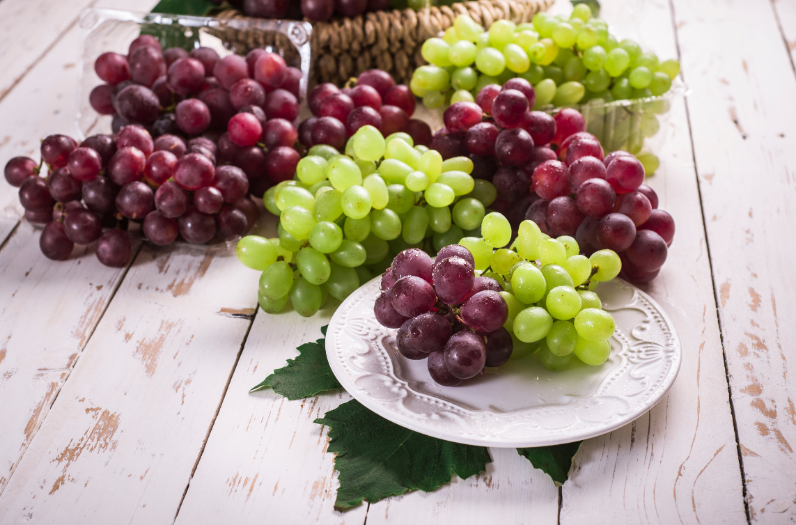 bunches of red and green grapes on a plate and on a table