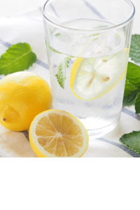 glass of water with a lemon slice and lemons and mint leaves beside the glass