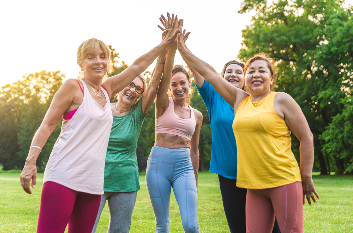 middle age women raising their hands in celebration after exercise